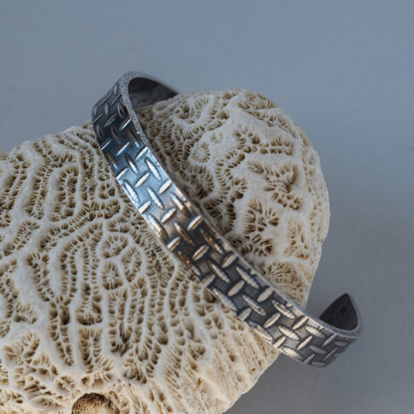 Silver tool cuff bracelet resting on a coral stone