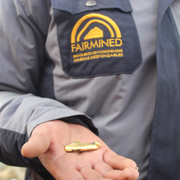 A man with a Fairmined uniform holding a patty of Fairmined gold in his hand