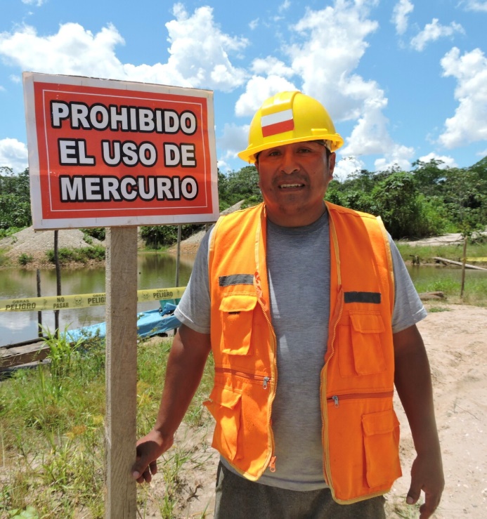 A man in hardhat and safety vest holding a sign in Spanish: Mercury Prohibited