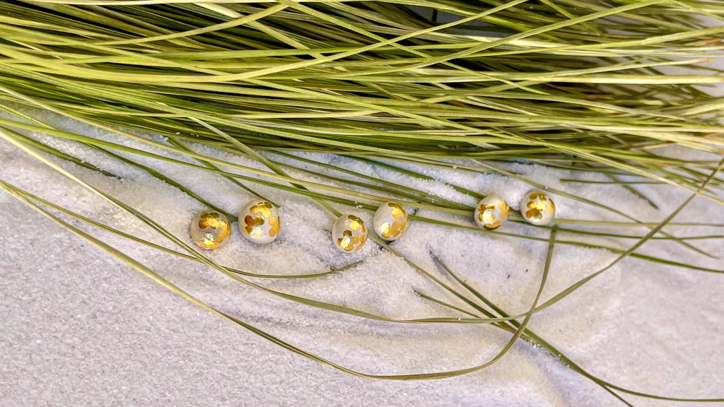 Gold gilded stud earrings on sea grass